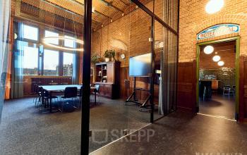 Sfeervolle kantoorruimte in het kantoorpand op Oudebrugsteeg 9, Amsterdam Centrum, voorzien van grote ramen en moderne inrichting.