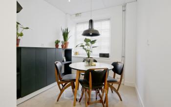 Stijlvolle kantoorruimte huren aan de Vrijheidslaan 80 in Amsterdam De Pijp, met een ronde tafel en stoelen, omringd door planten in een lichte, minimalistische setting.