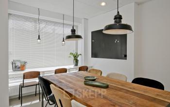 Rustiek ingerichte kantoorruimte aan de Vrijheidslaan 80 in Amsterdam De Pijp met houten tafel, fluwelen stoelen en grote ramen voor veel natuurlijk licht. Ideaal voor kantoor gebruik of vergaderingen.