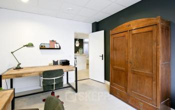 Kantoorruimte huren op Vrijheidslaan 80, Amsterdam De Pijp, met houten kast, bureau en groene stoel in modern interieur.
