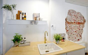 Interieur van een kantoor aan de Vrijheidslaan 80, Amsterdam De Pijp, met een houten aanrecht, geïntegreerde spoelbak en decoratieve bakstenen muur. Ideaal voor kantoorruimte huren.