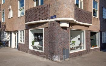 Bakstenen hoekpand op Vrijheidslaan 80 in Amsterdam De Pijp. Grote ramen bieden inzicht in de functies van het gebouw en zijn ideaal voor een kantoor.