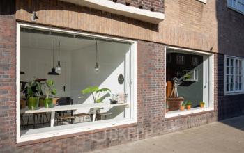 Voorgevel van kantoorpand op Vrijheidslaan 80 in Amsterdam De Pijp, met grote ramen die een blik bieden op het moderne interieur en de meubels.