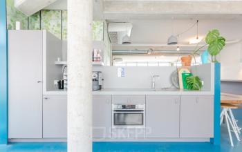 Moderne pantry met grijze kasten, oven, koffiezetapparaat en planten in kantoorpand op Generaal Vetterstraat 77e, Amsterdam De Schinkel.