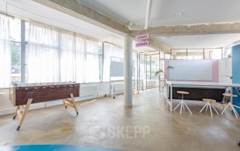 Lichte kantoorruimte te huur op Generaal Vetterstraat 77e, Amsterdam-De Schinkel, met tafelvoetbal, zitgedeelte en grote ramen.