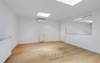 Open en lichte kantoorruimte te huur op Schinkelkade 44, Amsterdam De Schinkel, met houten vloer en een groot raam voor natuurlijk licht. Ideaal voor kantoren die een frisse werkplek zoeken.