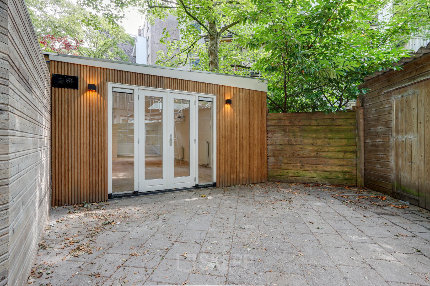 Exterieur van een kantoorpand met houten gevel en glazen deuren op Schinkelkade 44 in Amsterdam De Schinkel. Ideaal voor kantoorruimte huren met een rustige buitenruimte.