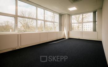 Lichte kantoorruimte te huur aan de Overschiestraat 182, Amsterdam De Schinkel, met grote ramen en uitzicht op bomen. Ideaal voor kantoorinrichting.
