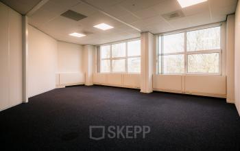 Ruime kantoorkamer op Overschiestraat 182, Amsterdam De Schinkel voor kantoorruimte huren. Grote ramen zorgen voor natuurlijk licht op de blauwe vloeren, ideaal voor een flexibel indeelbare werkruimte.