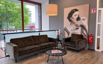 Loungegedeelte van het kantoorpand aan de Daalwijkdreef 47, Amsterdam Duivendrecht, met comfortabele zitplaatsen en een grote afbeelding aan de muur. Ideaal voor informele ontmoetingen of pauzes.