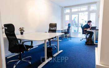 Licht kantoor op Herengracht 420, Amsterdam Grachtengordel, met werkplekken waar een persoon aan het werk is achter een laptop.