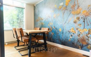 Vergaderruimte in kantoorpand op Keizersgracht 482, Amsterdam Grachtengordel met houten tafel, vijf stoelen en decoratieve muur.