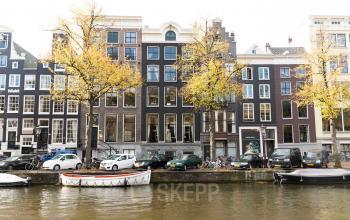 Kantoorpand aan de Keizersgracht 482 in de Amsterdam Grachtengordel, gezien vanaf de gracht met auto's en fietsen geparkeerd voor het gebouw.