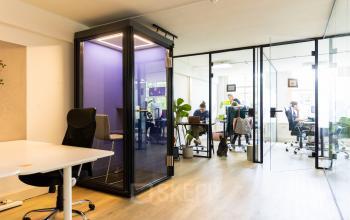 Zakelijke werkruimte in het kantoorpand op Keizersgracht 482, Amsterdam Grachtengordel met glazen wanden, moderne meubels en werkende mensen aan bureaus.