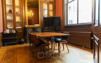 Kantoorpand aan Keizersgracht 482, Amsterdam Grachtengordel met een elegante vergaderruimte voorzien van houten tafel, stoelen en decoratieve haard.