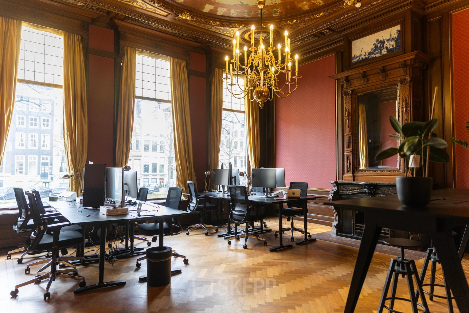 Kantoorruimte huren op Keizersgracht 482, Amsterdam Grachtengordel met stijlvolle inrichting, houten vloeren, open werkruimtes en computers op bureaus onder een luxe kroonluchter.