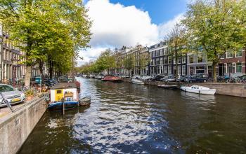 Sfeervolle gracht in Amsterdam met boten en historische panden, ideaal gelegen voor kantoorruimte huren aan de Keizersgracht 62-64.