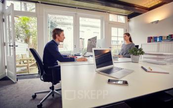 Twee mensen werken in een moderne kantoorruimte op Keizersgracht 62 – 64, Amsterdam Grachtengordel. Het kantoorpand heeft ruime werkplekken met veel daglicht. Ideaal voor kantoorruimte huren.