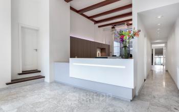 Heldere receptieruimte van kantoorpand op Keizersgracht 62 – 64, Amsterdam Grachtengordel, met moderne balie, marmeren vloer en bloemstuk, ideaal voor kantoorruimte huren.