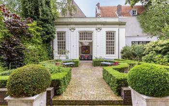 Buitengevel van kantoorpand aan de Keizersgracht 62-64 in Amsterdam Grachtengordel, met een groene tuin en zitbanken voor kantoorruimte huren.