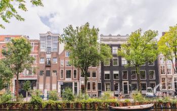 Buitenzicht op kantoorpand aan de Herengracht in Amsterdam Grachtengordel, met historische gevels en bomen langs de gracht.
