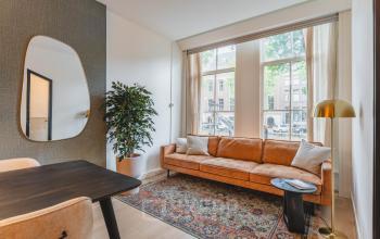 Gezellige kantoorruimte huren op Herengracht 221, Amsterdam Grachtengordel, met een comfortabele bank, een grote spiegel en een stijlvolle inrichting.