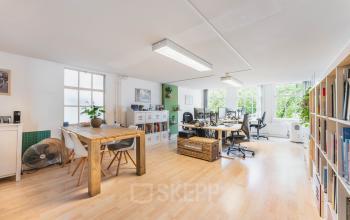 Kantoorruimte op Herengracht 221 in Amsterdam Grachtengordel, een lichte en gemeubileerde werkruimte met houten tafels en moderne bureaus voor huur.