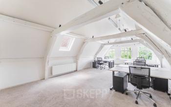 Lichte kantoorruimte op Herengracht 221 in Amsterdam Grachtengordel met houten balken, bureaus en bureaustoelen, ideaal om te huren.