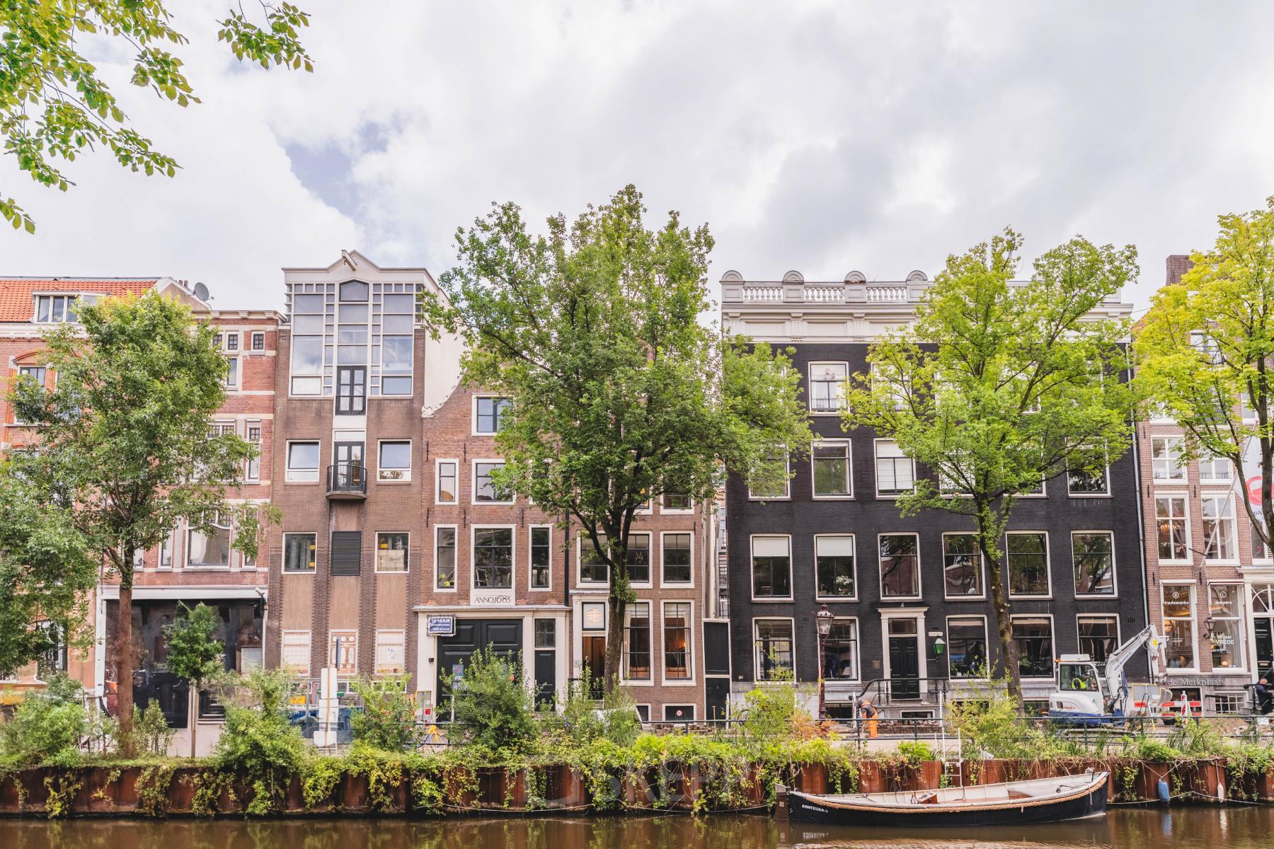 Buitenzicht op kantoorpand aan de Herengracht in Amsterdam Grachtengordel, met historische gevels en bomen langs de gracht.