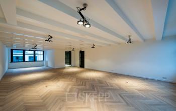 Moderne, verlichte kantoorruimte aan Keizersgracht 119 met visgraatvloer en grote ramen met uitzicht op de grachten van Amsterdam.