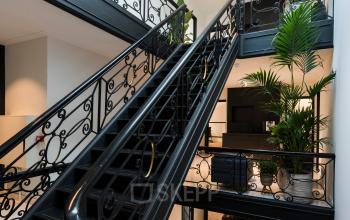 Interieur van het kantoor op Keizersgracht 121, Amsterdam Grachtengordel met een elegante, zwart gesmede trap en planten. Dit kantoorpand biedt een stijlvolle ambiance ideaal voor huur.
