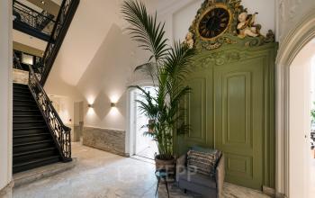 Entree van kantoor aan de Keizersgracht 121, Amsterdam Grachtengordel, met marmeren vloer, groene deur met klok en grote plant. Ideale locatie voor kantoorruimte huren.