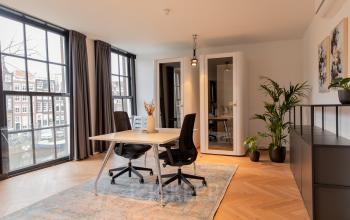 Moderne kantoorruimte met glazen wanden aan de Keizersgracht 121, Amsterdam, met stijlvolle inrichting en een bureau. Geschikt voor zakelijk gebruik in de Amsterdam Grachtengordel.