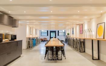 Kantoor op Keizersgracht 121 in Amsterdam met moderne werkruimte en lange houten tafel, geschikt voor vergaderingen. Heldere verlichting en minimalistisch interieur. Ideaal voor wie kantoorruimte wil huren in de grachtengordel.