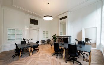Stijlvolle kantoorruimte aan de Keizersgracht 121, Amsterdam Grachtengordel met houten vloer, moderne bureaus en stoelen, verlicht door een opvallende hanglamp, geschikt voor huren. Geen personen aanwezig. Strakke, professionele uitstraling.