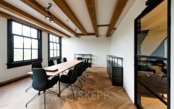 Interieur van een kantoorpand op Keizersgracht 121 in Amsterdam Grachtengordel, met een lange houten tafel en moderne stoelen geschikt voor vergaderingen. Grote ramen zorgen voor natuurlijke lichtinval.