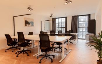 Interieur van kantoorpand op Keizersgracht 121, Amsterdam Grachtengordel met ruime werkplekken voorzien van moderne stoelen en bureaus. Grote ramen bieden uitzicht op de gracht terwijl kunst aan de muur hangt.