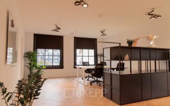 Lichte kantoorruimte in Amsterdam Grachtengordel met houten vloer en werkplekken, geschikt voor kantoorruimte huren.