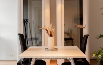 Modern kantoorpand aan de Keizersgracht 121, in Amsterdam Grachtengordel, met twee bureaustoelen aan een tafel en planten in de hoek.