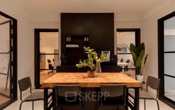 Moderne en strakke kantoorruimte met een houten tafel en planten op Keizersgracht 121 in Amsterdam Grachtengordel. Zicht op open vergadertafels en lichte wanden, ideaal om te huren.