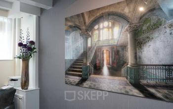 Interieur van kantoorpand aan Herengracht 449a in Amsterdam Grachtengordel met kunst aan de muur en bloemenvaas, lichte en rustige omgeving.