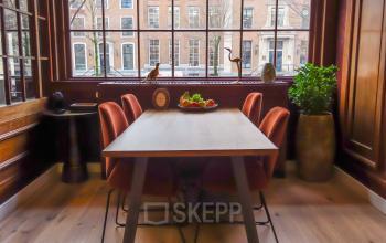 Vergaderruimte in kantoorpand aan Herengracht 449 a in Amsterdam Grachtengordel met houten tafel, rode stoelen en uitzicht op grachtenpanden.