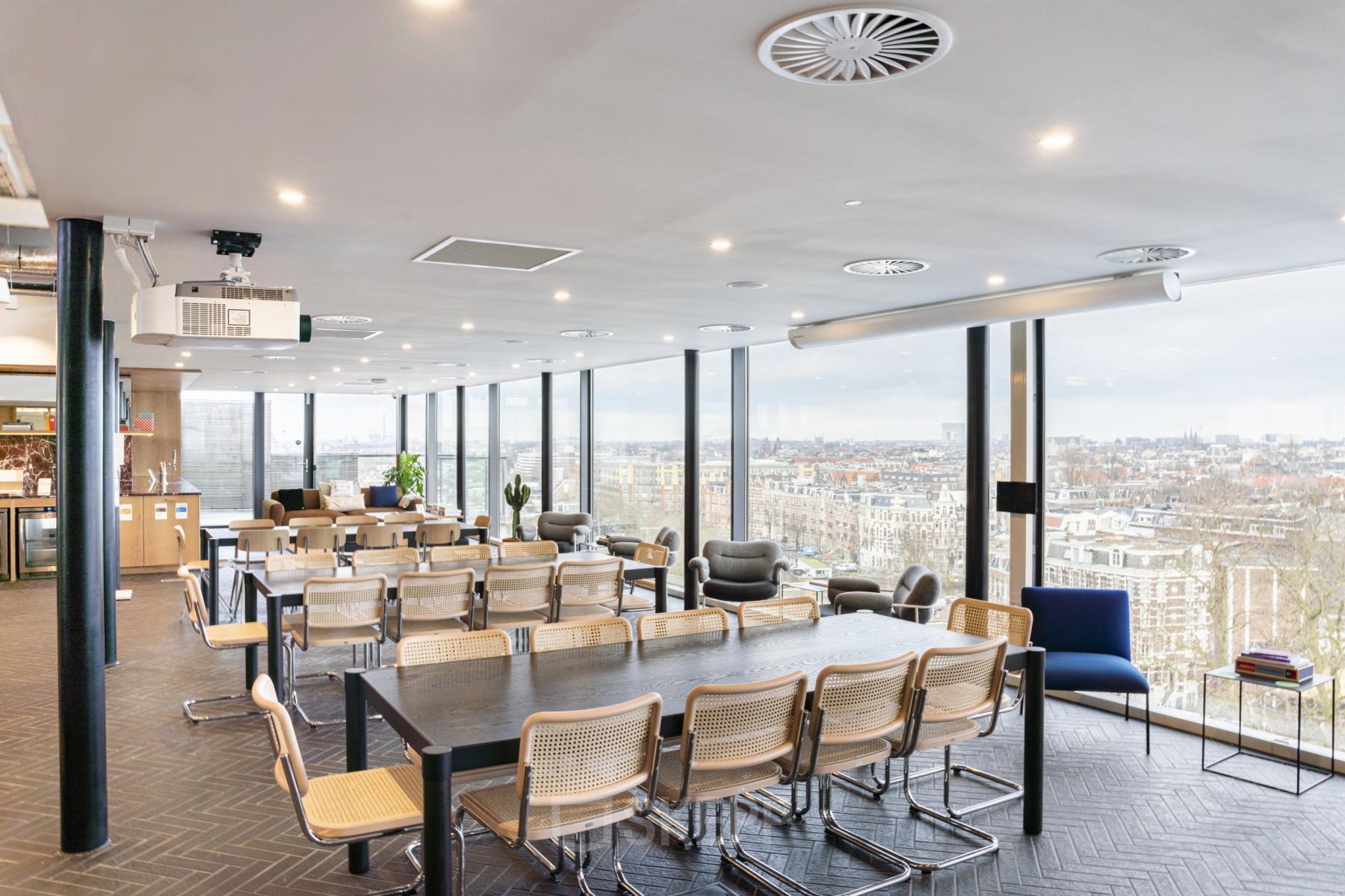 Lichte en ruime conferentieruimte met uitzicht over Amsterdam, geschikt voor zakelijke bijeenkomsten. De kamer is modern ingericht met stoelen en tafels, ideaal voor kantoorruimte huren aan de Stadhouderskade 5-6.