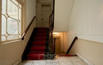 Ingang van een kantoorpand op Keizersgracht 391A, Amsterdam Grachtengordel, met rood gestoffeerde trap en marmeren vloer. Een ideale plek voor kantoorruimte huren.