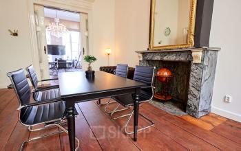 Kantoorruimte huren aan de Keizersgracht 391A in Amsterdam Grachtengordel met een professioneel ingerichte vergaderruimte, voorzien van houten vloer, elegante haard en stijlvolle vergadertafel.