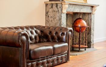 Kantoorruimte aan de Keizersgracht 391A in Amsterdam met een leren fauteuil voor een klassieke marmeren open haard en een globe. Authentieke setting voor kantoor huren.