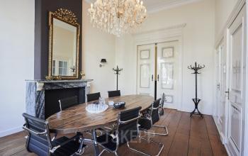 Stijlvolle vergaderruimte in een kantoorpand aan de Keizersgracht 391A, Amsterdam Grachtengordel, met houten tafel, designstoelen en een sierlijke kroonluchter. Ideaal voor kantoorruimte huren met karakter.