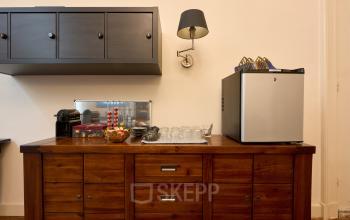 Gezellige pantry in kantoorpand aan de Keizersgracht 391A met houten kast, koffiezetapparaat en glazen. Ideaal voor kantoorruimte huren in Amsterdam Grachtengordel.