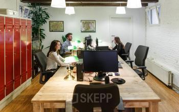 Werkruimte in het kantoorpand Vinkenstraat 79 HS in Amsterdam Grachtengordel met houten tafels, kasten en mensen in zakelijke activiteit.