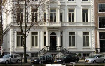 Kantoorpand aan de Keizersgracht 452, Amsterdam Grachtengordel. Klassiek pand met witte gevel, geparkeerde auto's en een boot aan de kade.